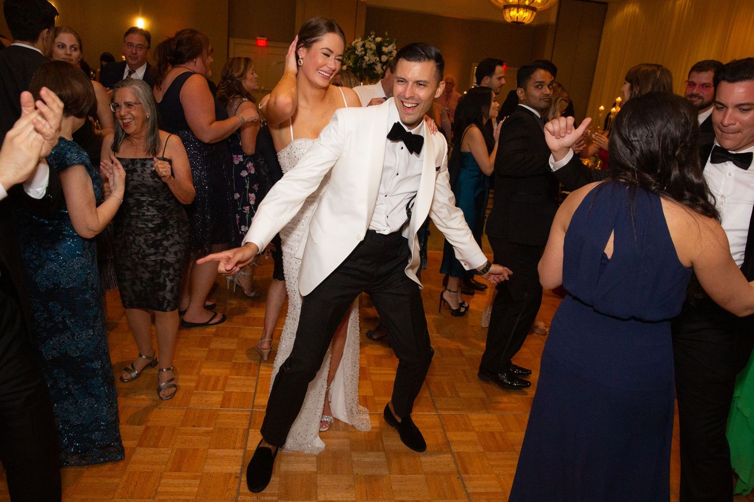 Wedding reception dance party in full swing with guests in formal attire.