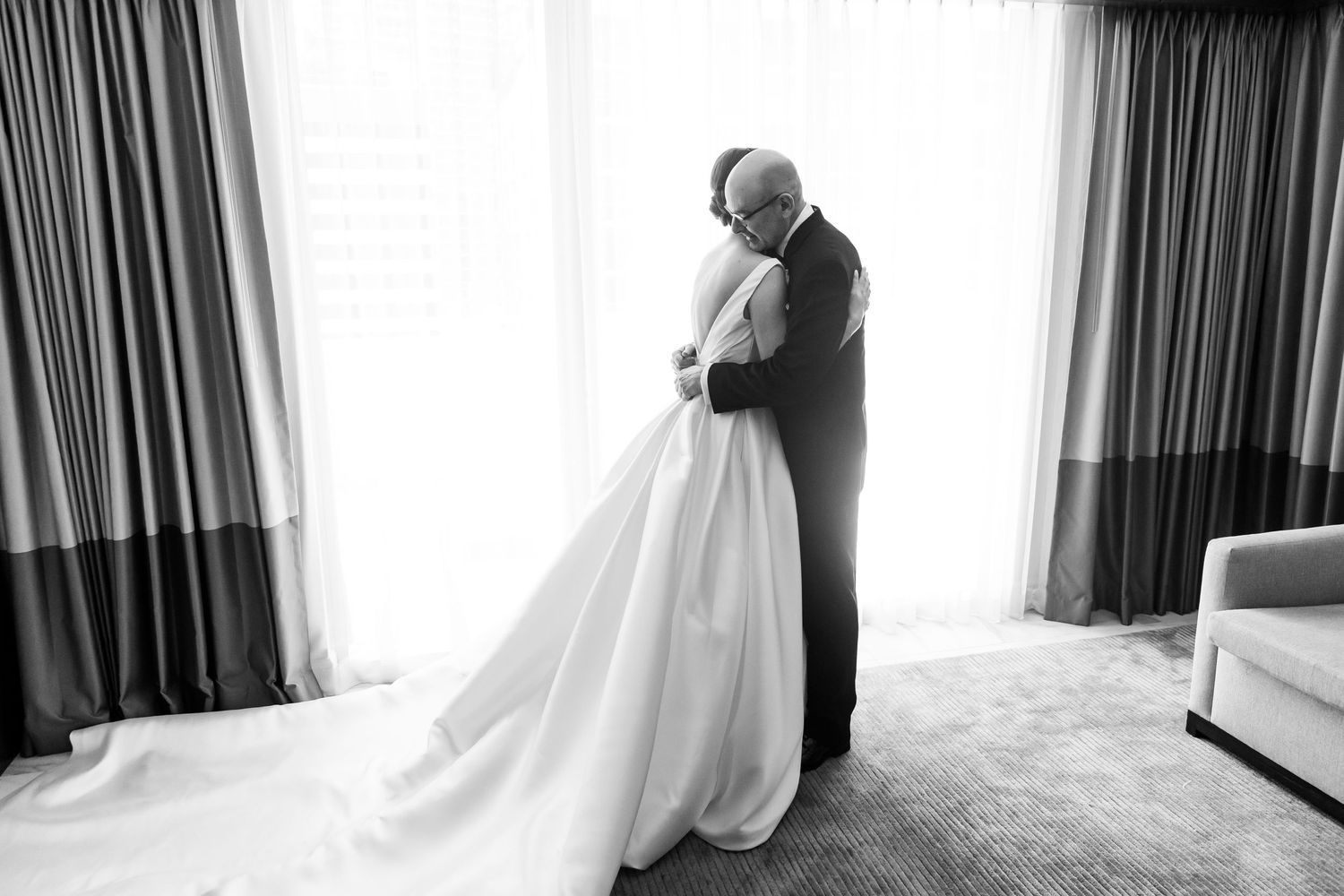 Black and white wedding photography showing intimate moments through curtained window.
