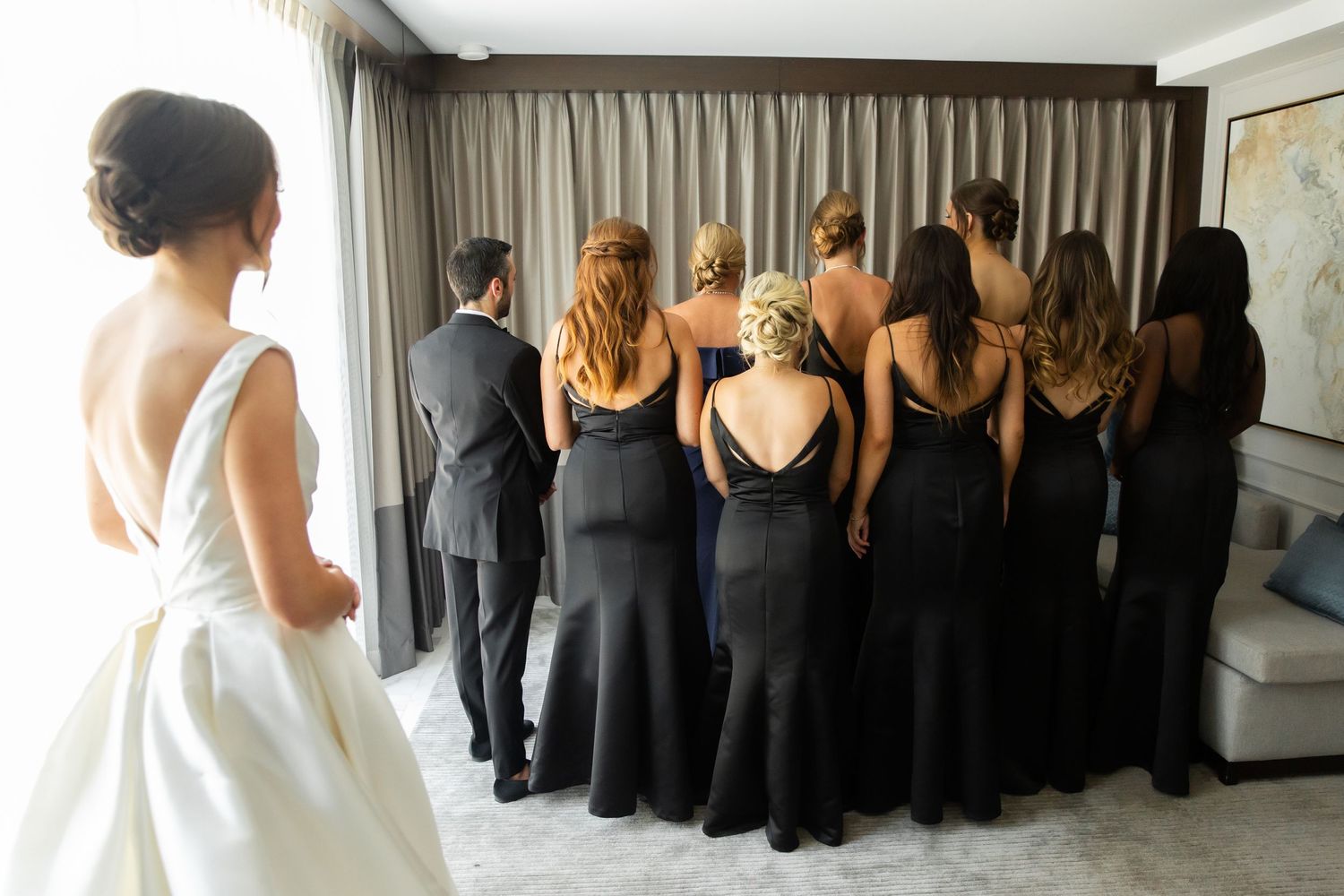 Wedding party lineup with bridesmaids in black dresses and bride in white gown.
