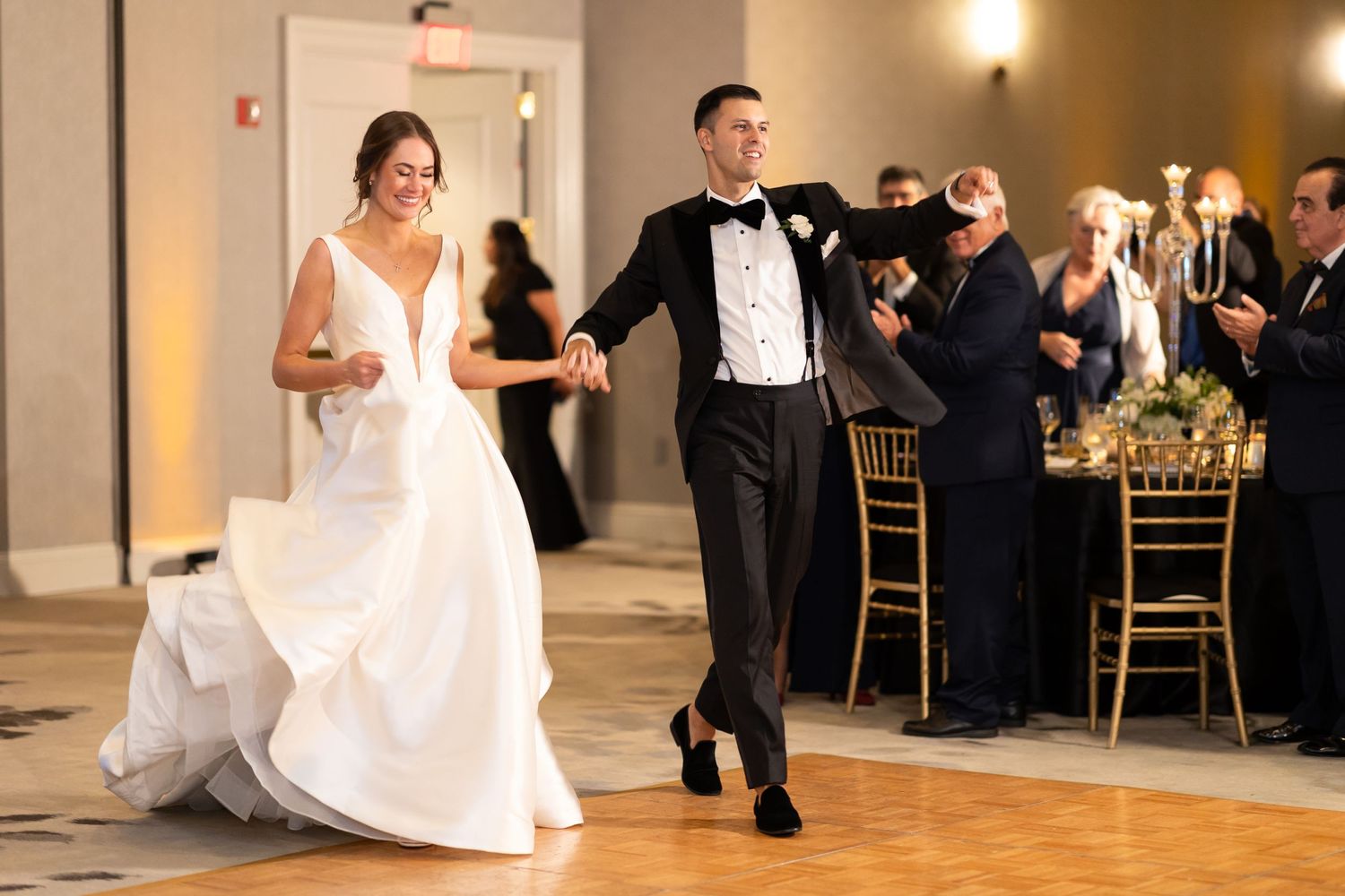 Wedding celebration with dancers performing on a wooden ballroom floor.
