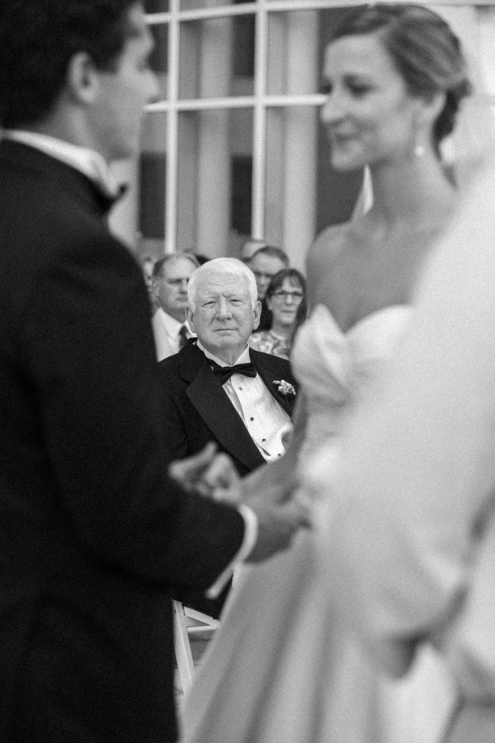 A candid moment of joy at a wedding celebration with guests in formal attire gathered together.