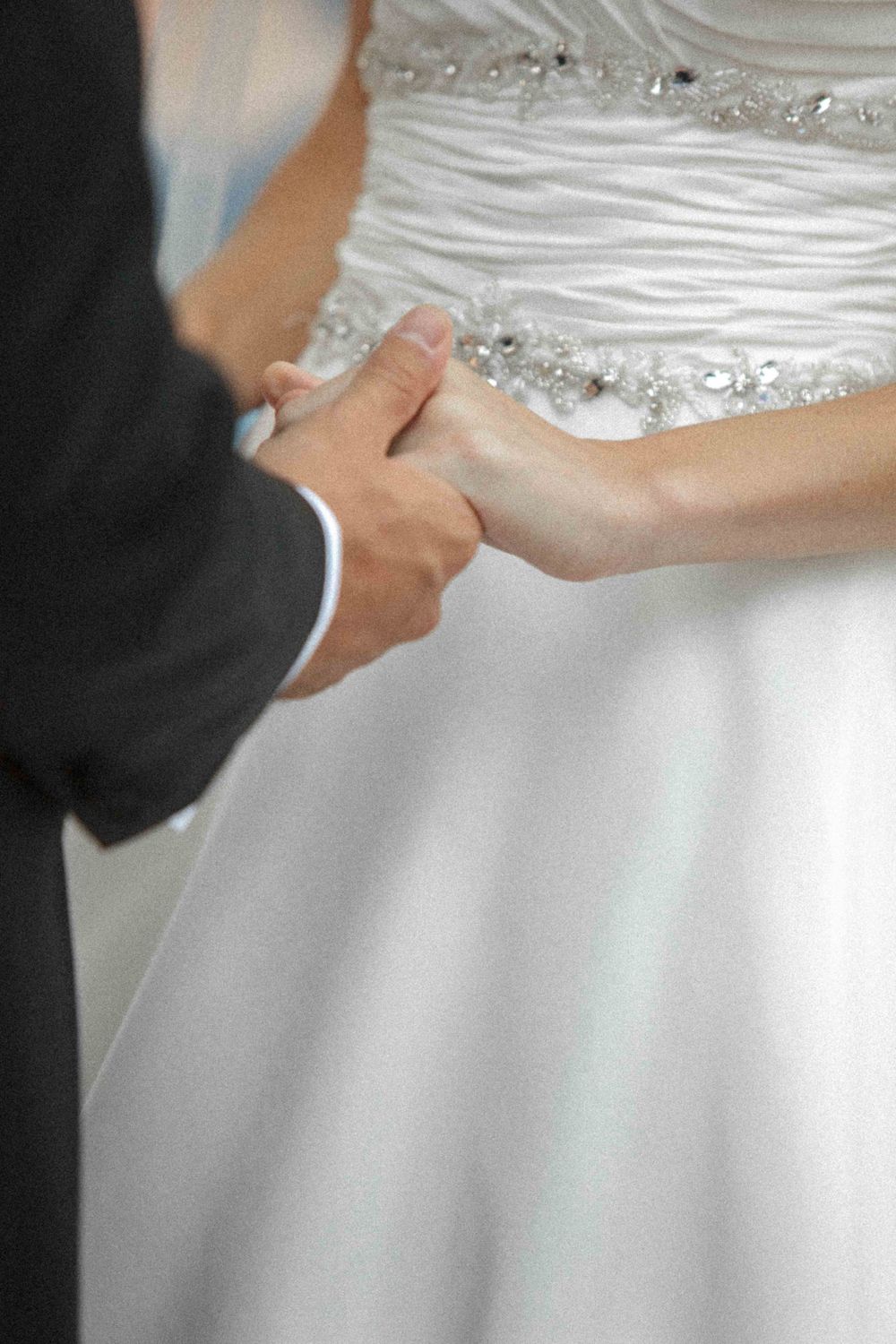 Close-up shots of a couple holding hands wearing formal wedding attire with white dress and dark suit details.