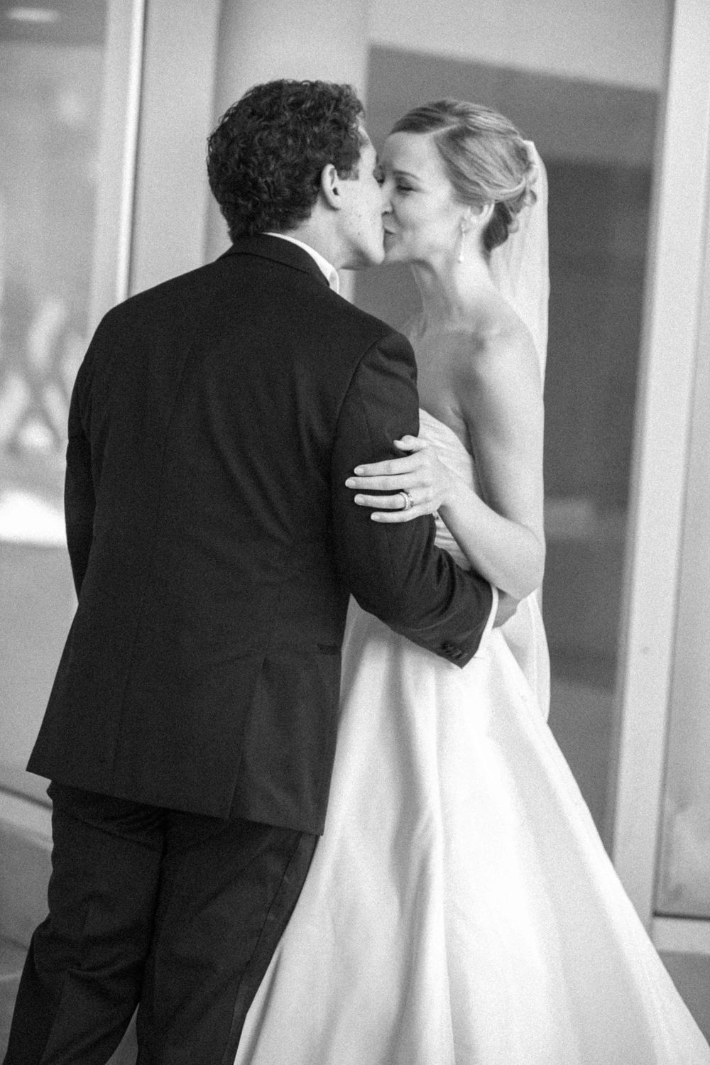 Black and white wedding photography series showing romantic kissing sequence between newlyweds in formal attire.