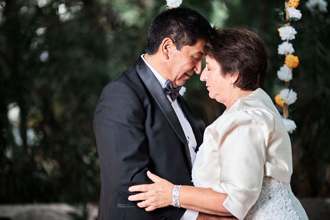 Intimate moment shared between a mature couple during an elegant outdoor wedding ceremony.