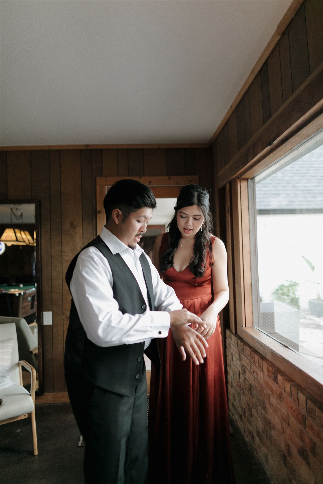 An intimate moment captured by a window in a rustic wood-paneled room.
