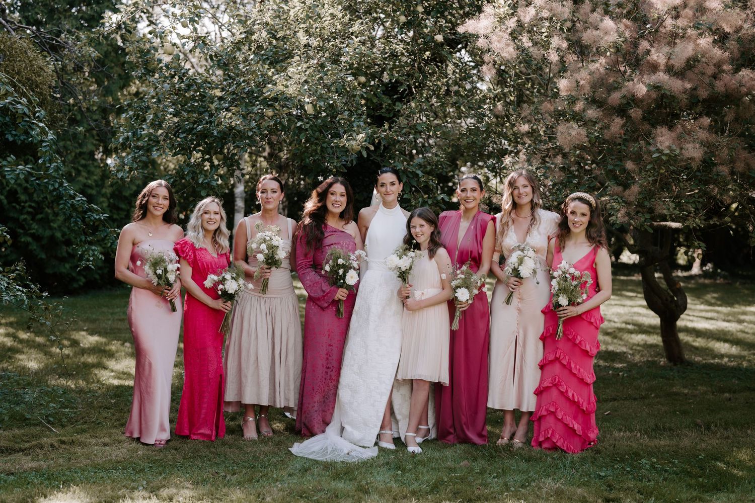bride and bridesmaids stood in orchard smiling for a portrait in islip Oxfordshire