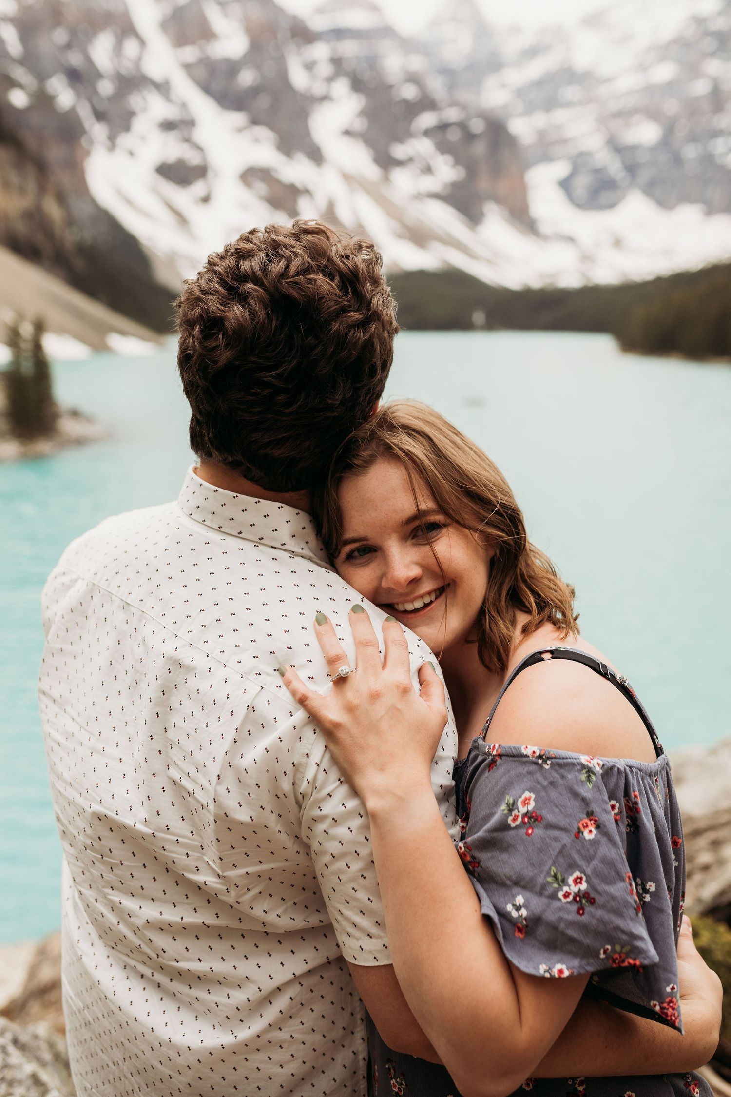 A romantic moment shared between a couple at a stunning mountain lake viewpoint.
