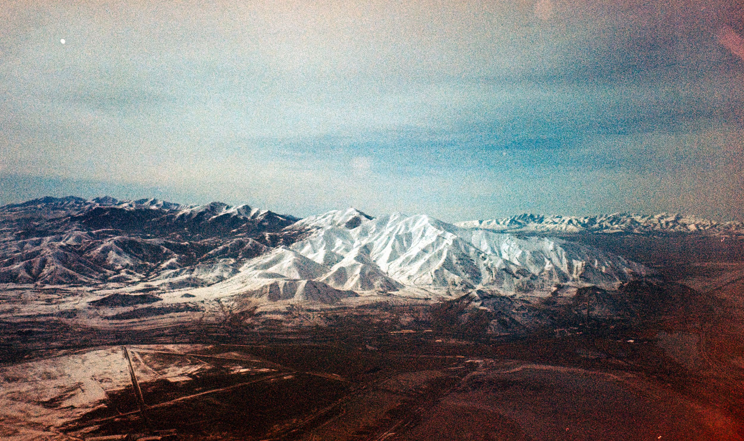 Snow-capped mountain range under blue sky photographed in vintage style.