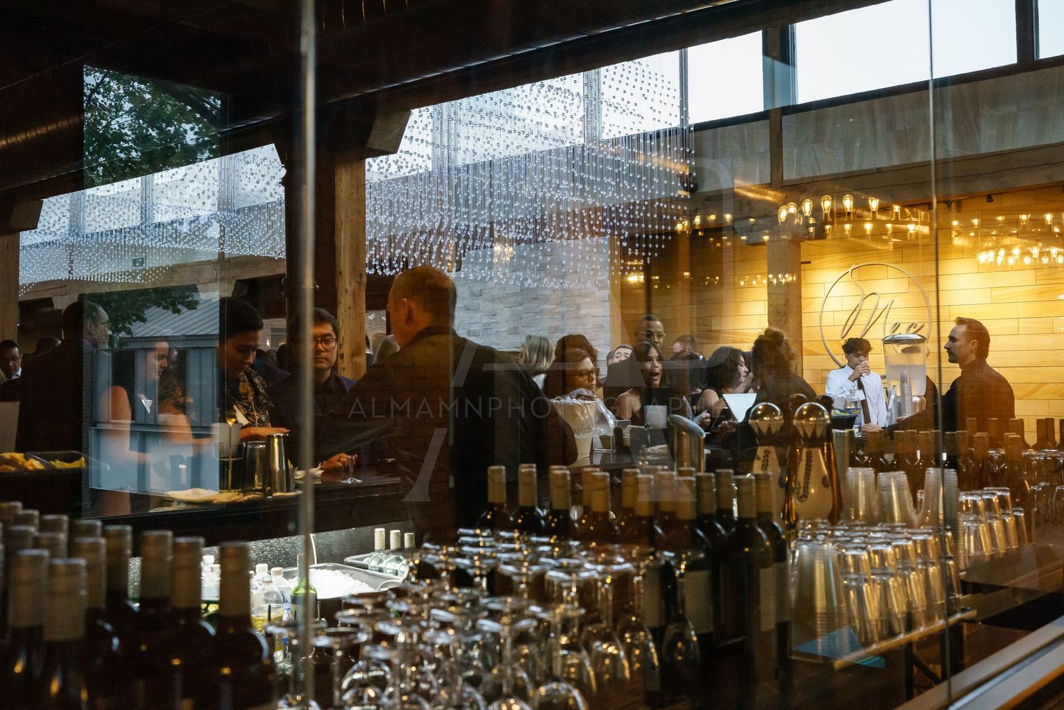Bar interior with glassware and bottles backlit by window light.