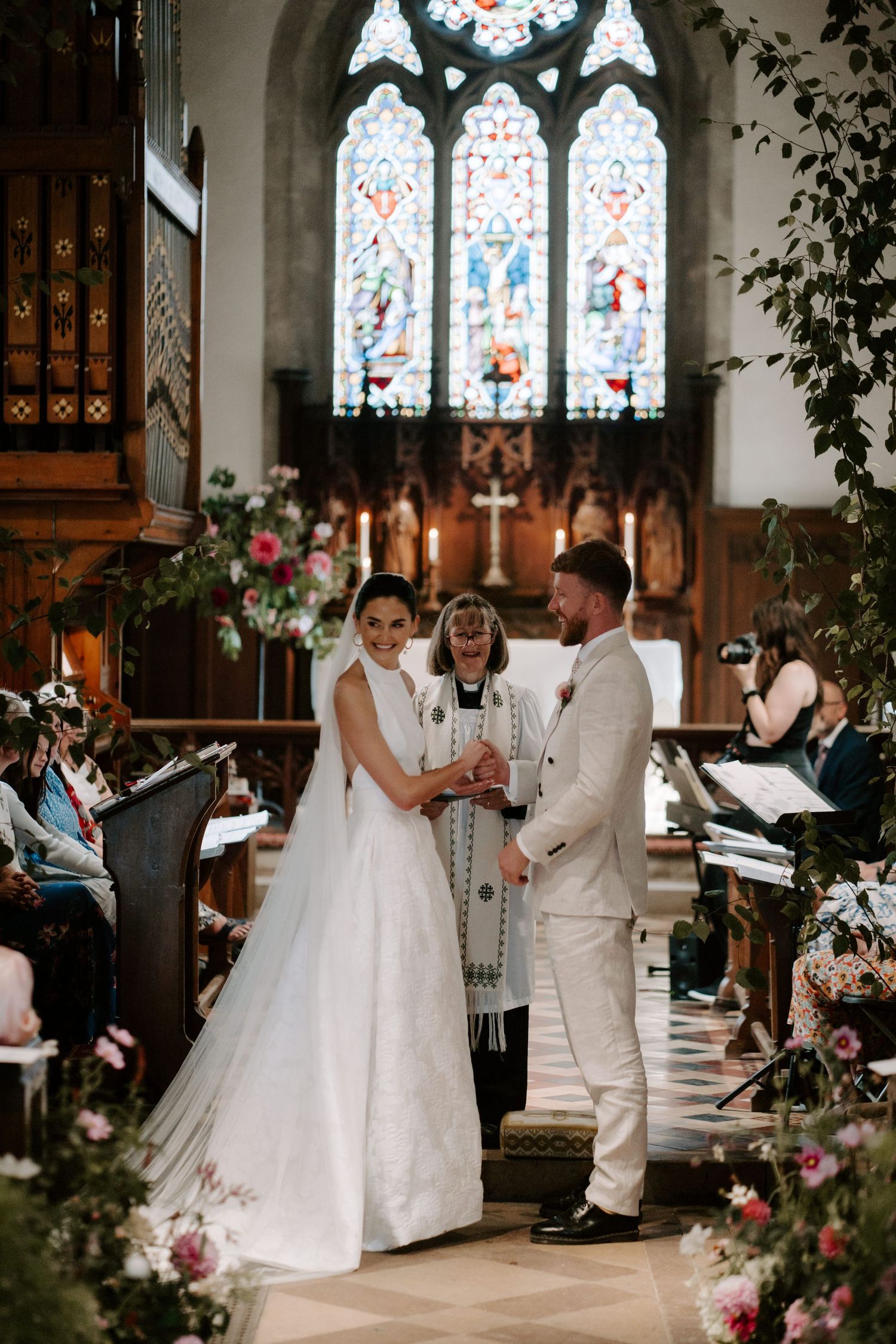 bride and groom smiling at wedding guests at the church alter at st Nicholas church in Oxfordshire