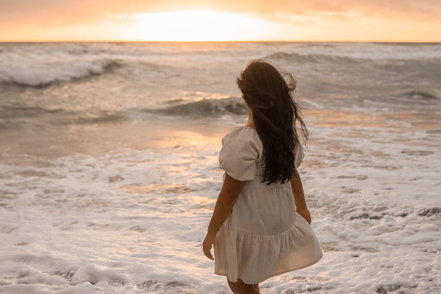 Woman stands on the beach looking at the sunset in Stuart, Florida