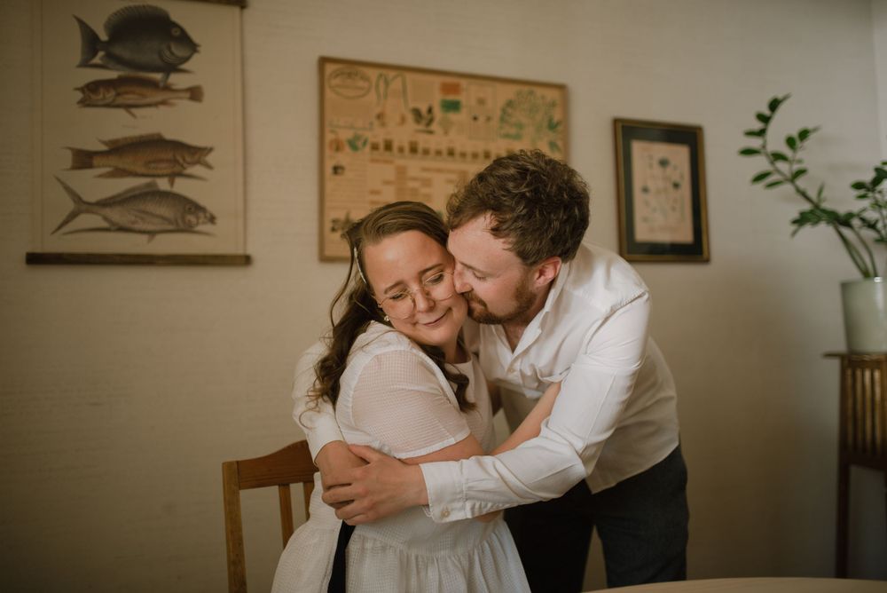 An intimate embrace captured in a room with vintage fish prints on the wall.