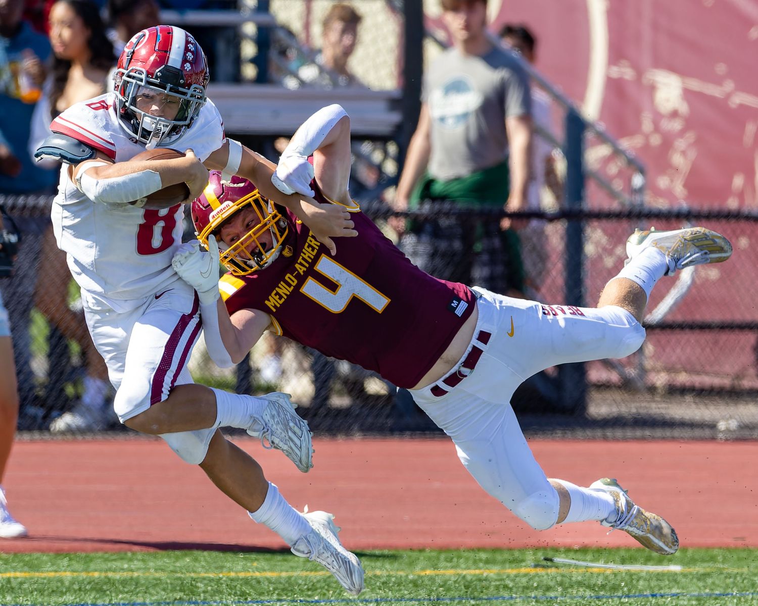 Action shot of football players colliding during an intense tackle play on the field.