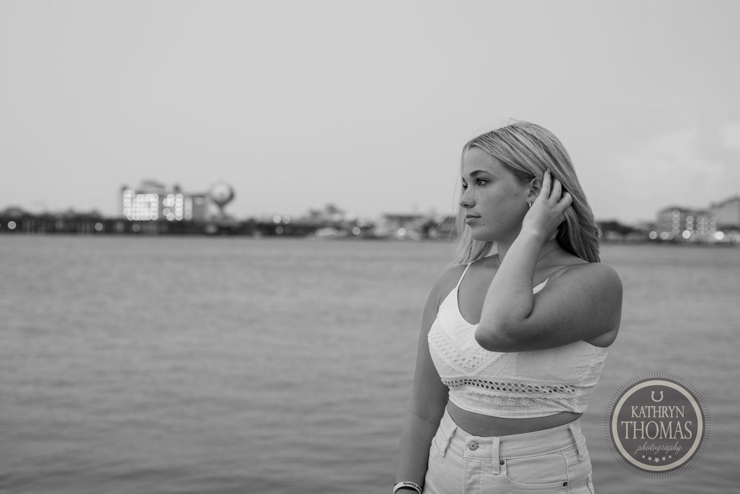 Waterfront portrait in black and white with industrial buildings visible in the distance.
