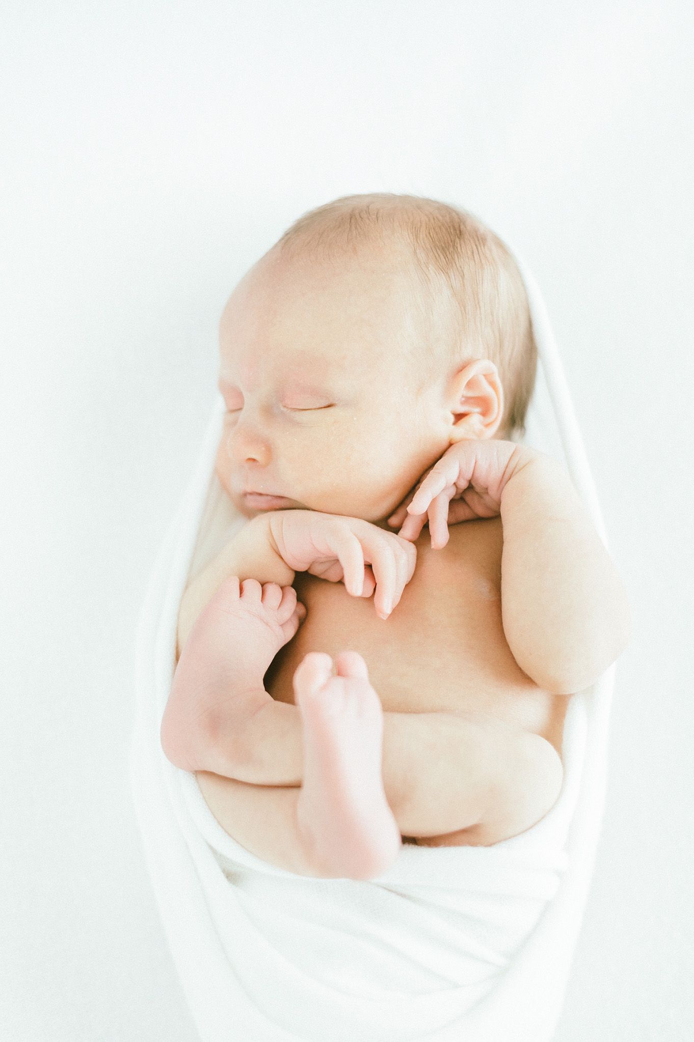 Serene newborn baby sleeping peacefully against white background.