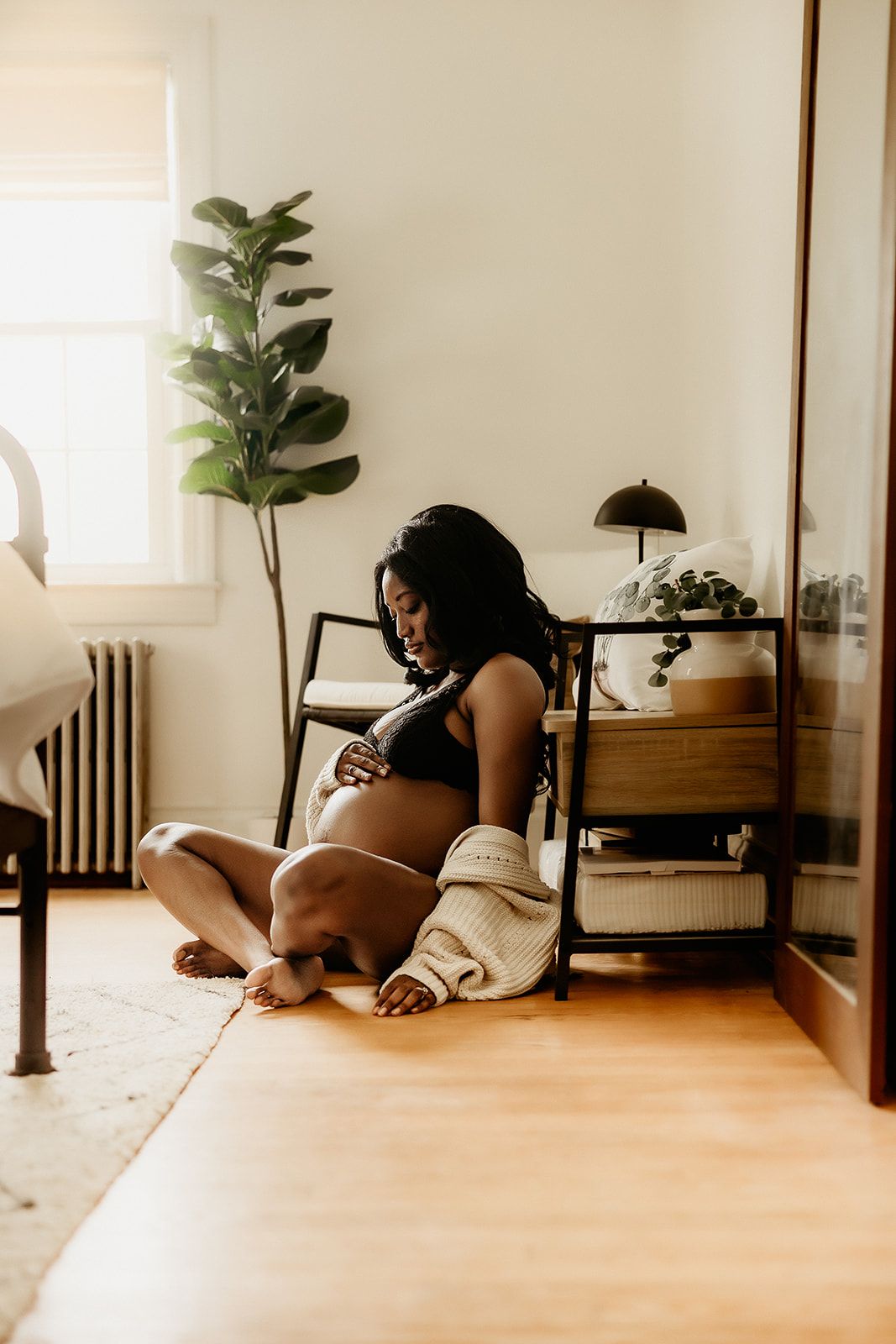 A mother sits on the floor holding her baby bump during her Charlottesville Maternity Session.
