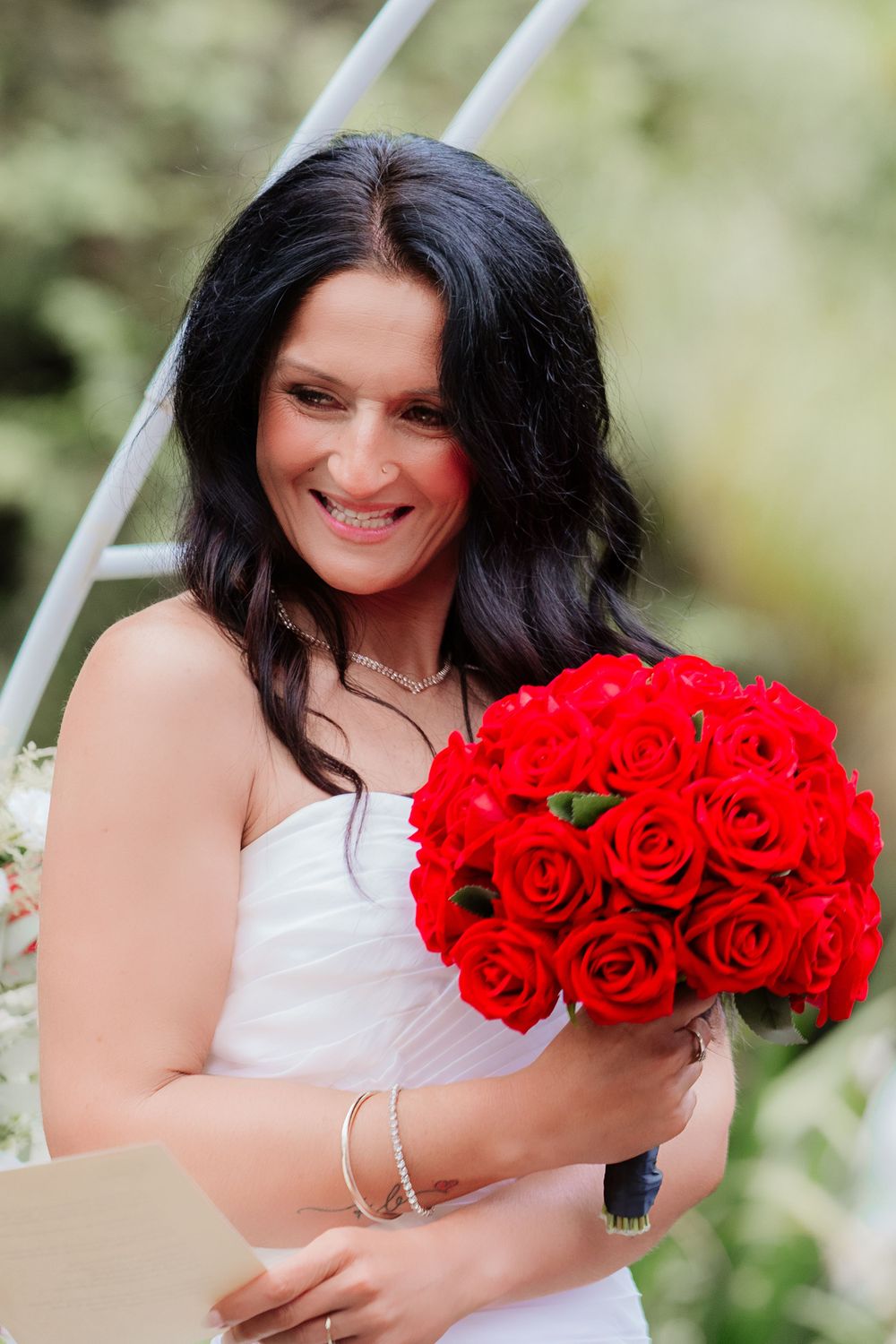 A stunning bouquet of bright red roses being held against a white dress.