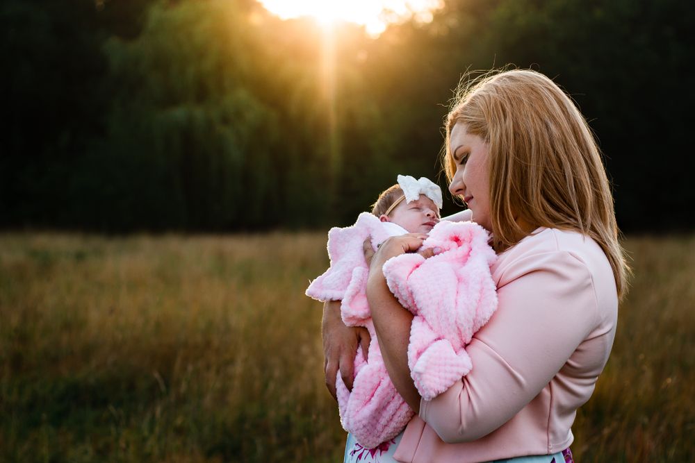 In a field in Havant a New Mum cradles her Newborn daughter in the last rays of light.
