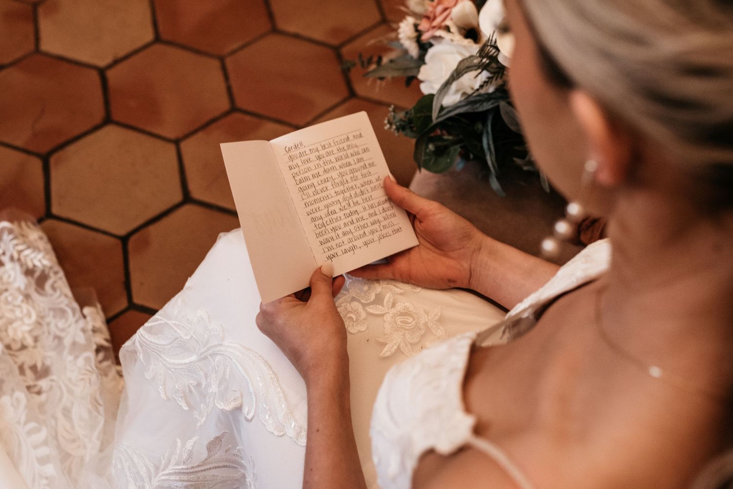 Overhead view of someone in a wedding dress reading a handwritten note.