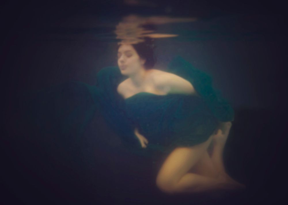Underwater photo of a pregnant lady serenely floating in the water.