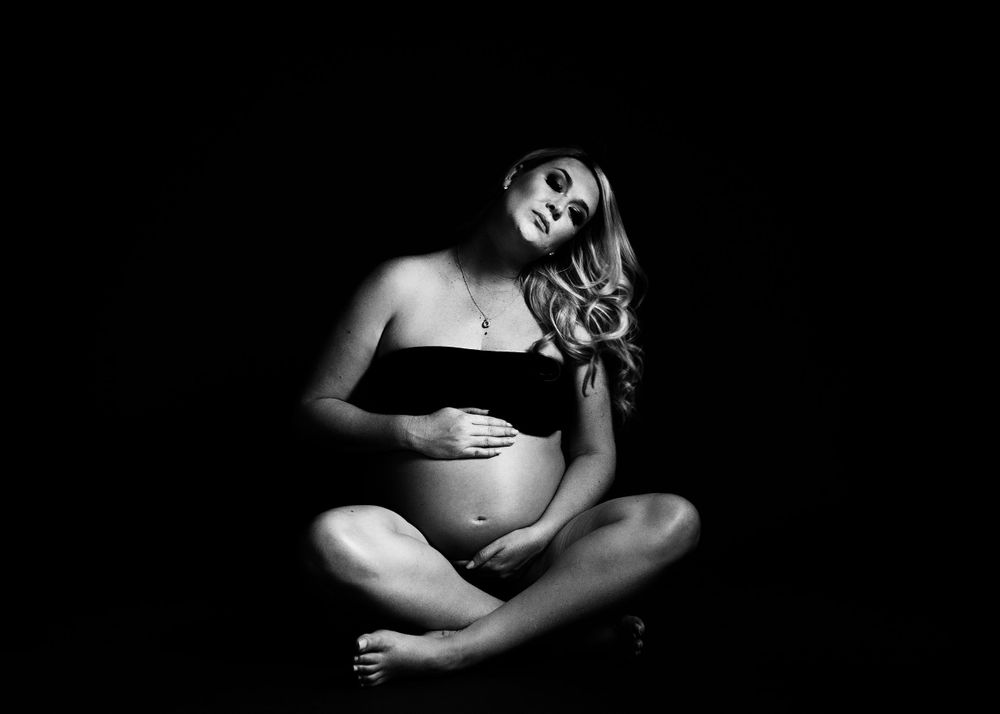 Black and white image of pregnant lady hugging her belly.