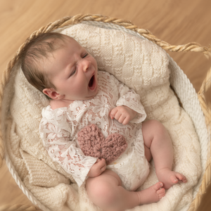 newborn baby girl photo with crochet heart pink baby yawning in basked knitted blanket cream