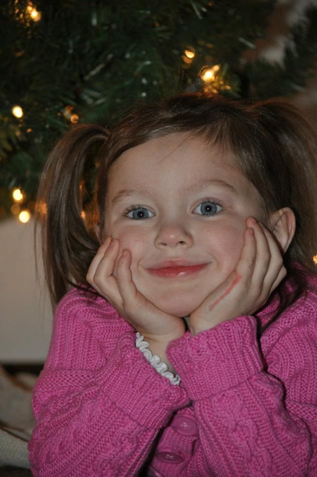 A festive holiday portrait with twinkling Christmas tree lights in the background.