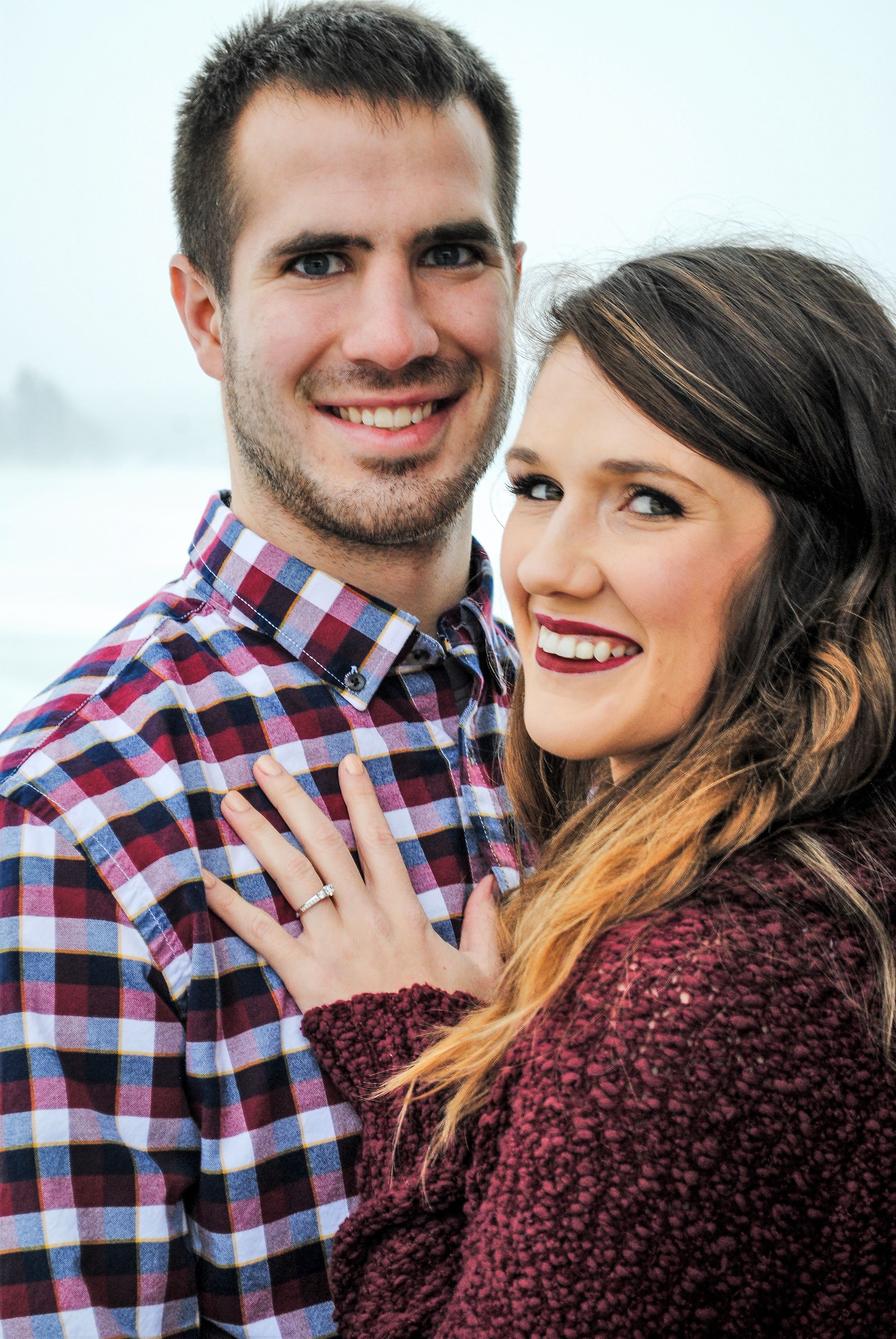 Couple in plaid and burgundy sweater pose together in romantic outdoor portrait.