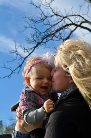 A tender moment captured against a blue sky with bare tree branches in the background.