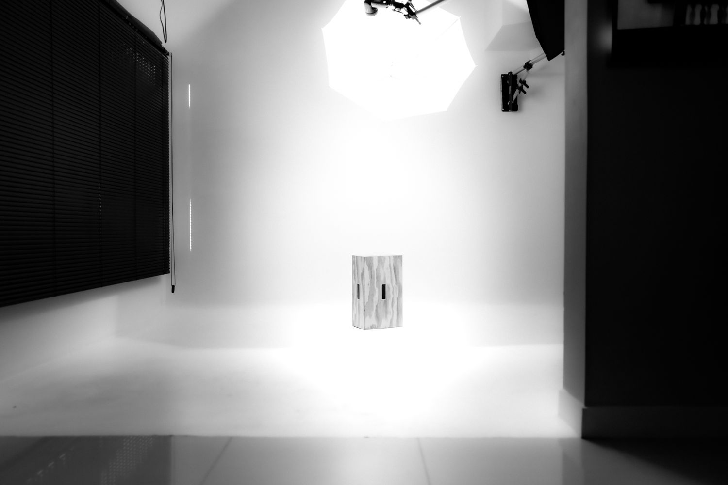 Minimalist white photography studio space with lighting equipment and dark walls.