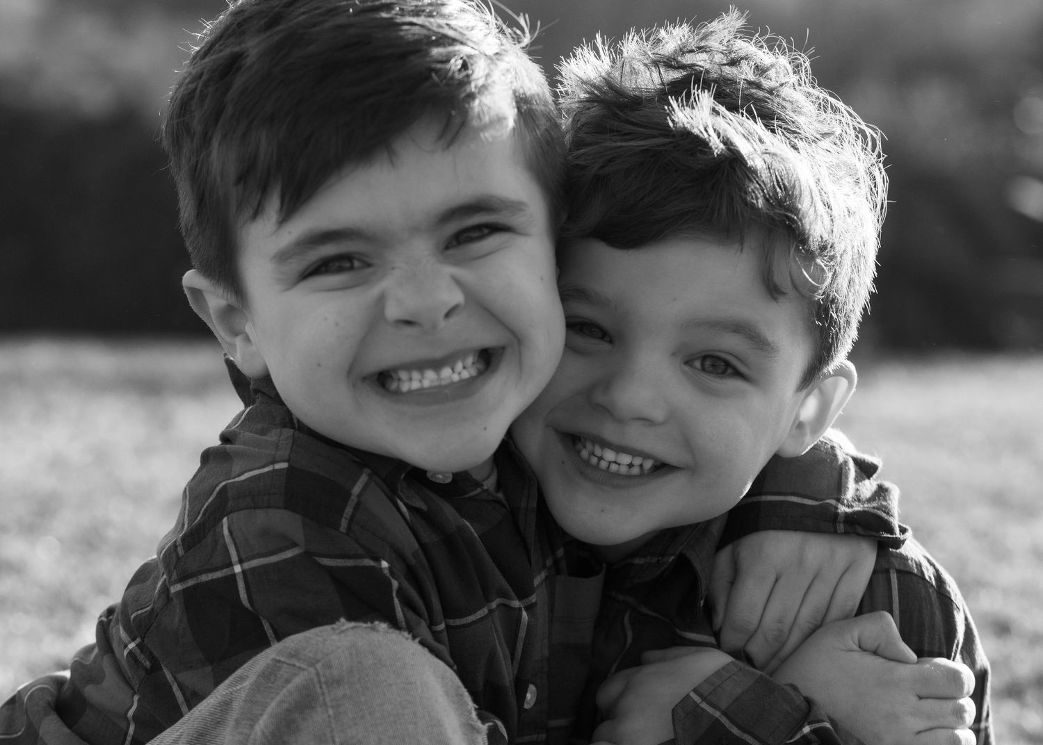 Black and white photo series showing two children laughing and embracing in an outdoor setting in Rhode Island.