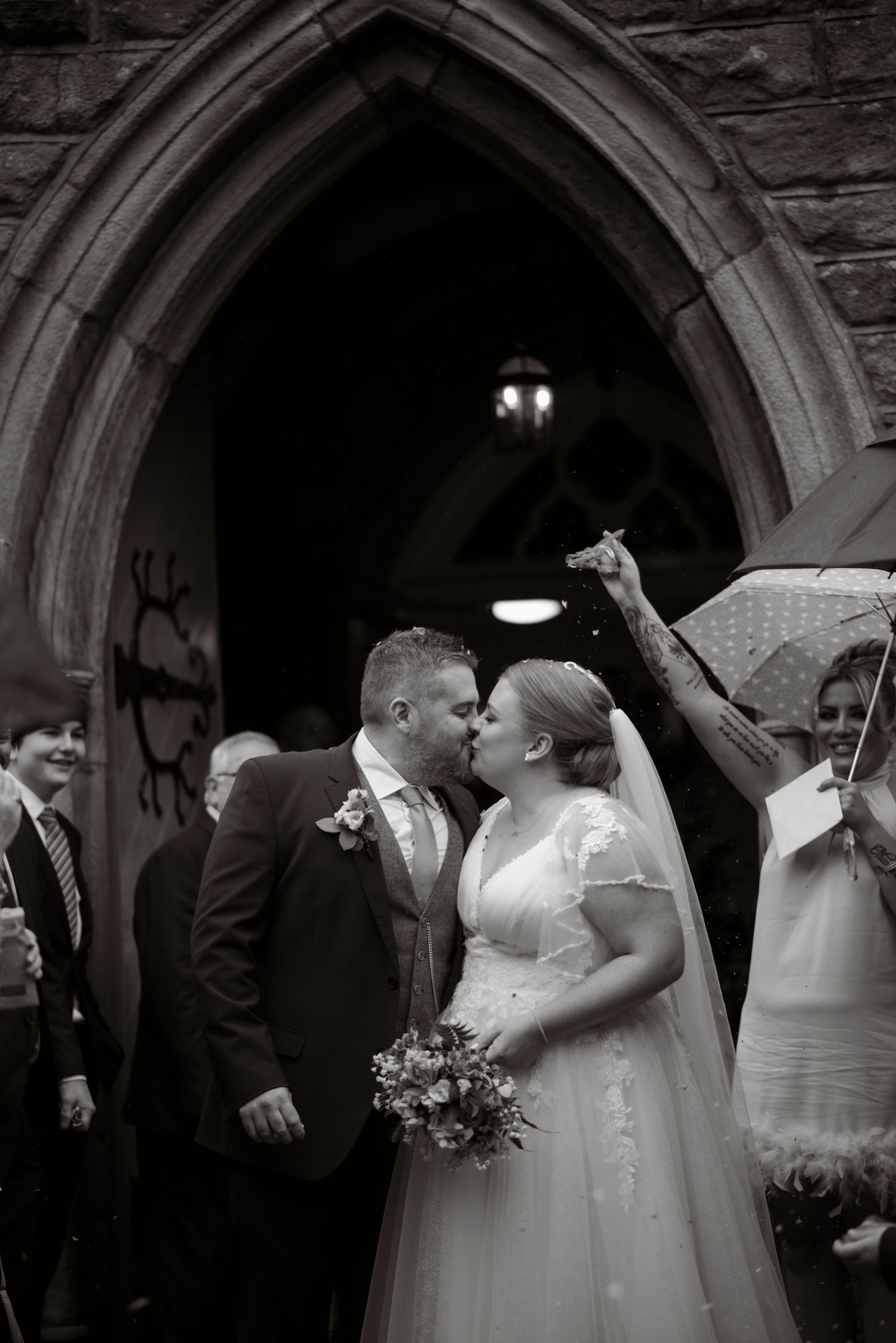 black and white portrait of a bride and groom kissing during confetti exit, sheffield wedding