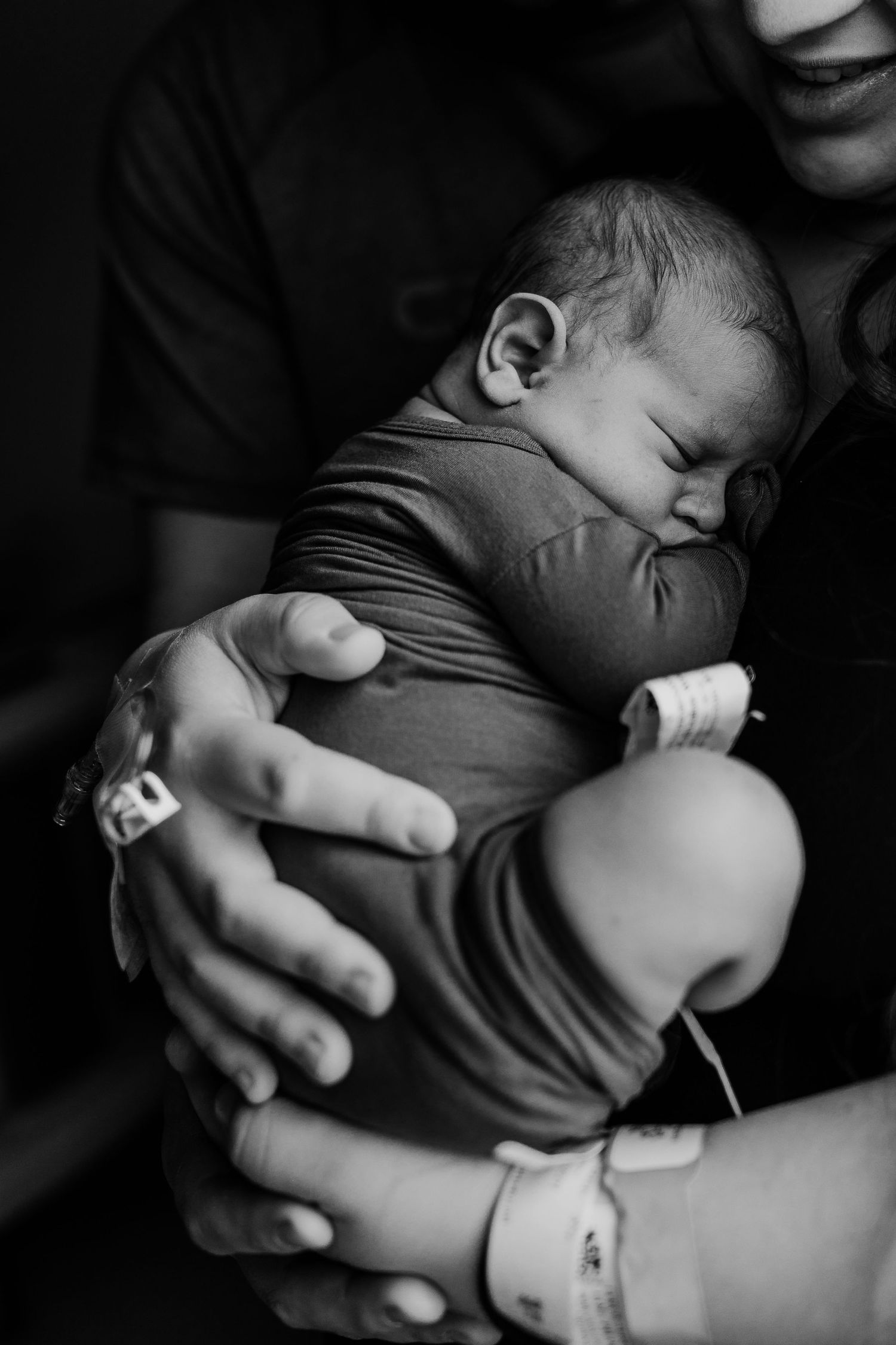 Black and white photo of sleeping infant being cradled in gentle embrace.