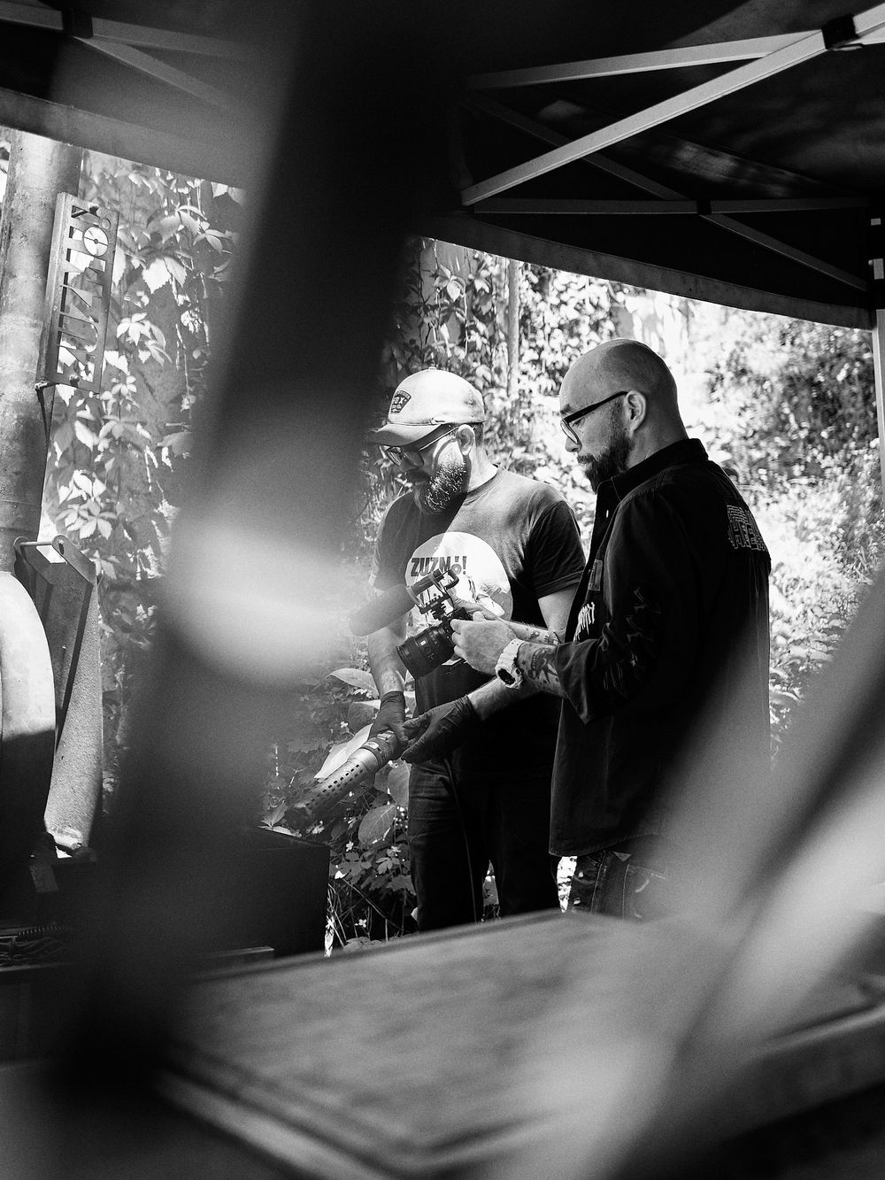 Black and white image of outdoor BBQ preparation scene with smoker equipment.