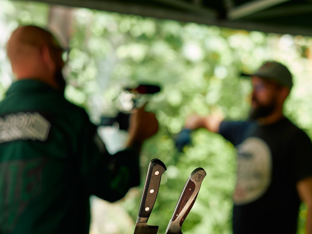 Blurred silhouettes of people filming food preparation with professional camera equipment.