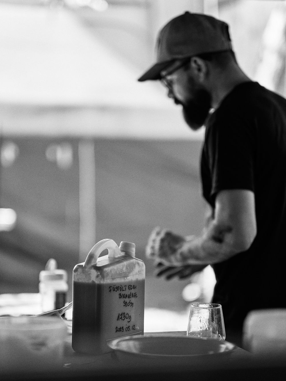 Black and white profile shot of person working at outdoor food station.