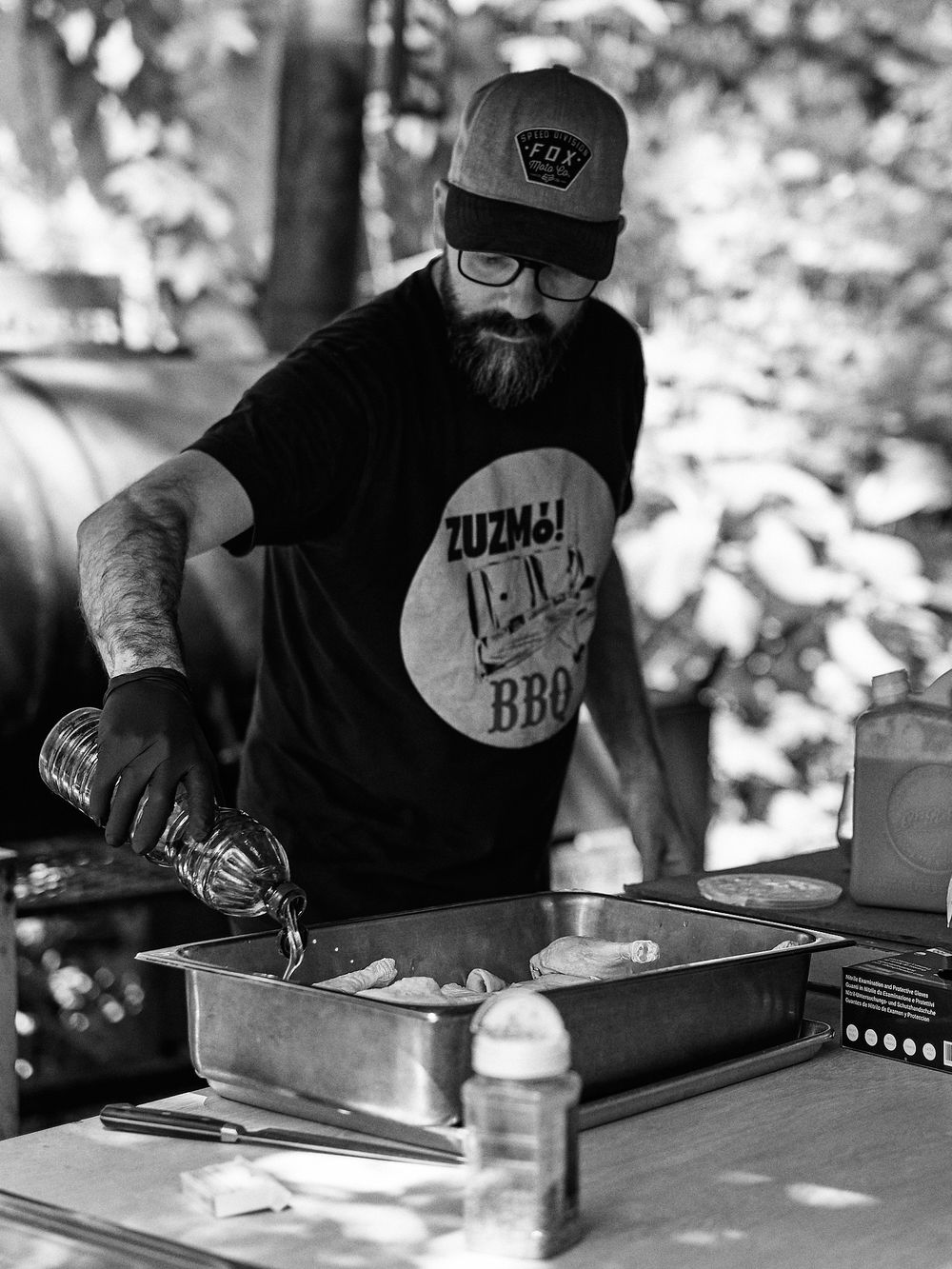 Black and white photo showing BBQ preparation at outdoor cooking station.