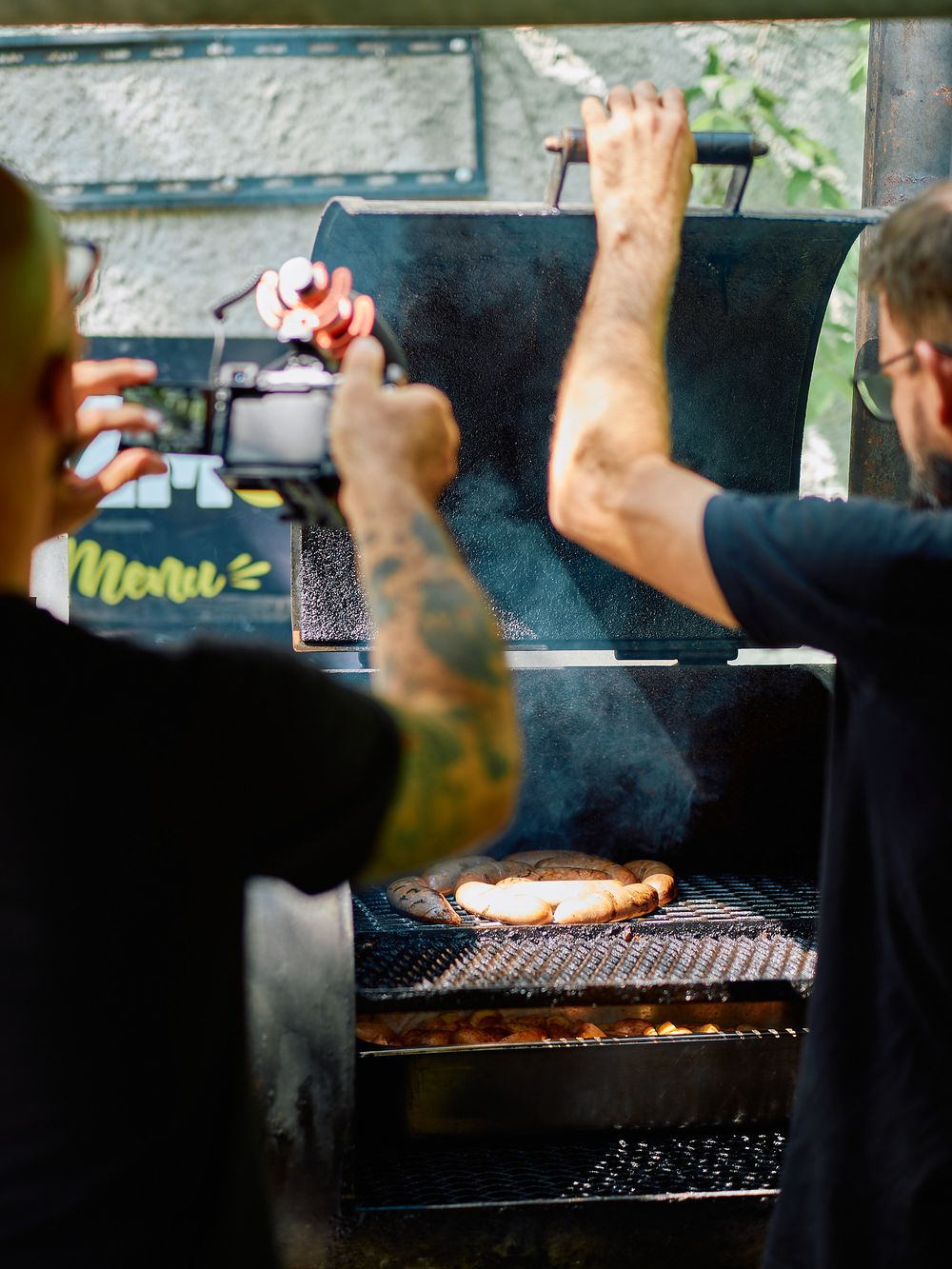 Back view of BBQ grill master preparing meat on smoking grill.