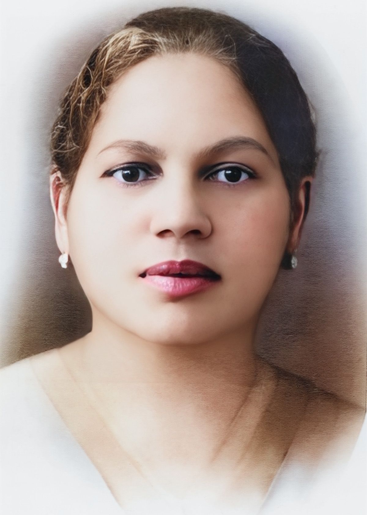 Professional portrait photo in soft focus with white top and earrings against blurred background.