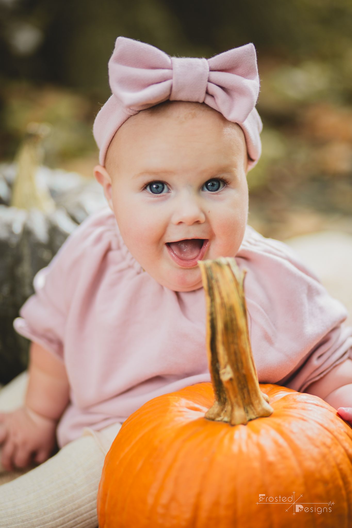6 month old girl with pumpkin and a great big smile.