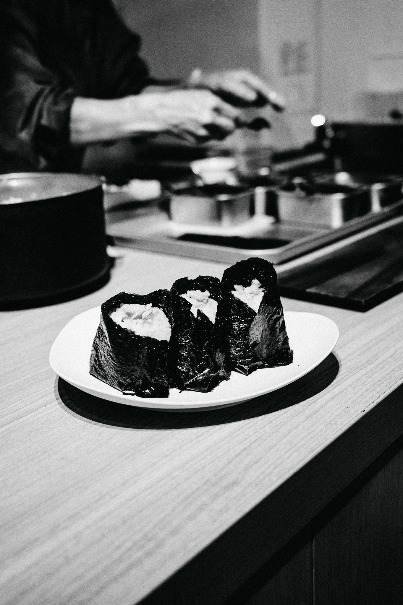 Fresh sushi rolls with white filling wrapped in dark nori seaweed on a white plate.