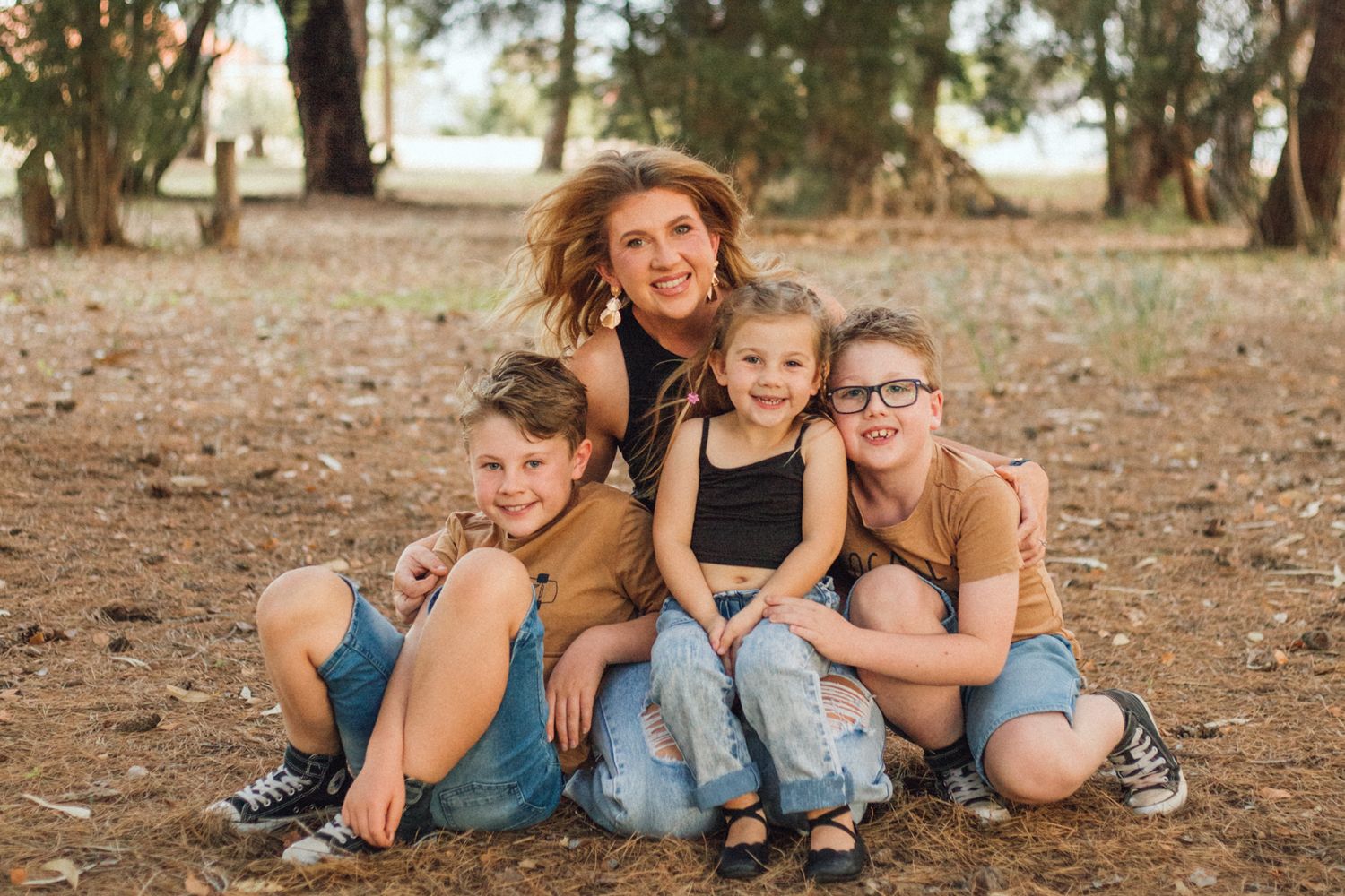 mother and her two sons and one daughter cuddling together smiling