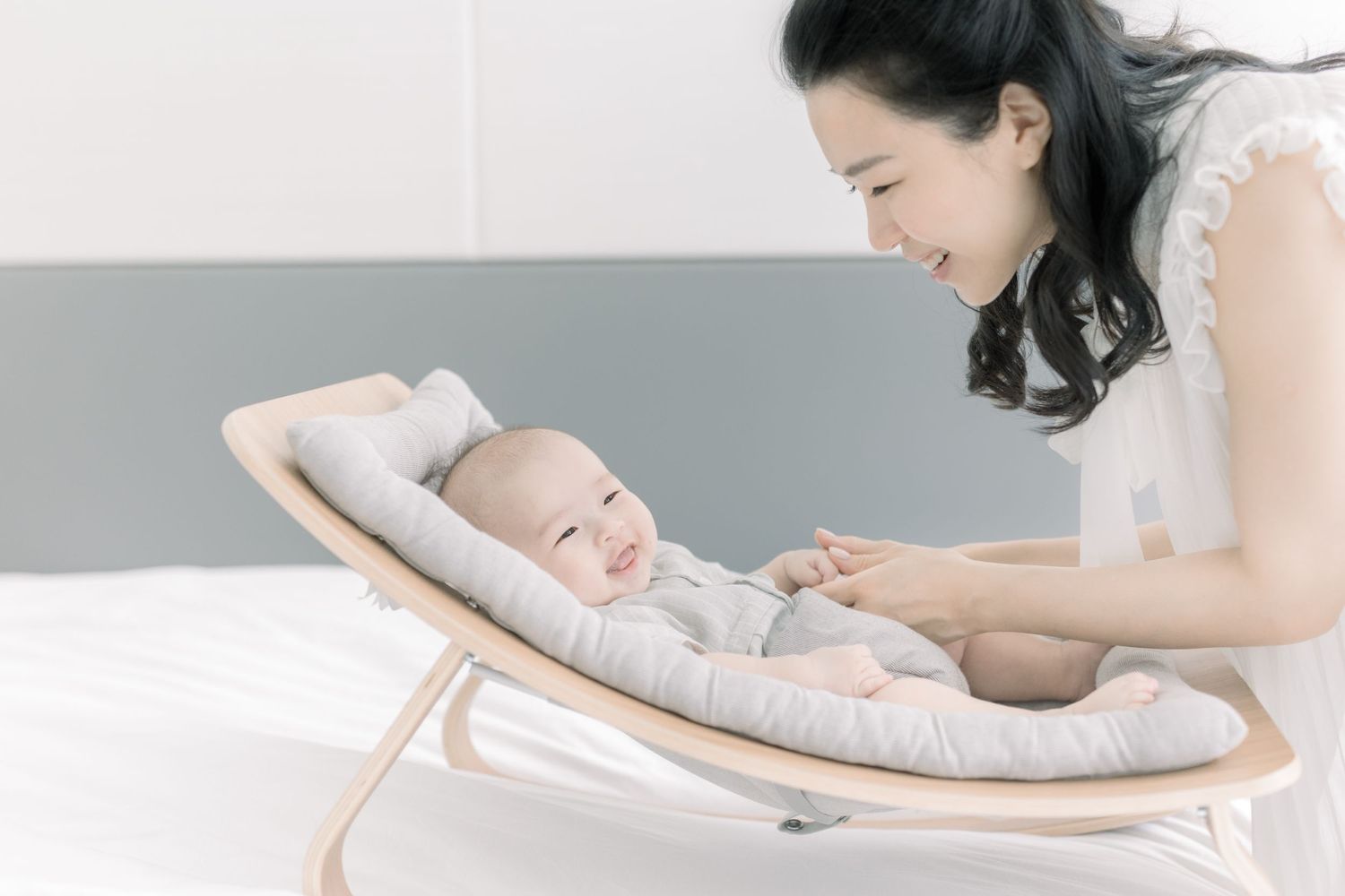 Baby lies contentedly in a modern curved bouncer chair.