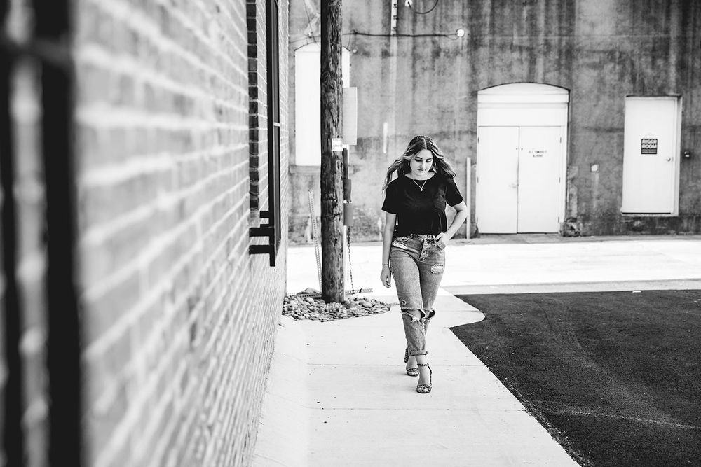 senior girl walking by a brick wall in an alley way