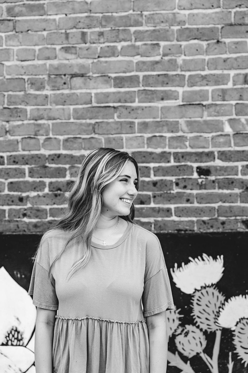 senior girl smiling to the side in front of mural wall