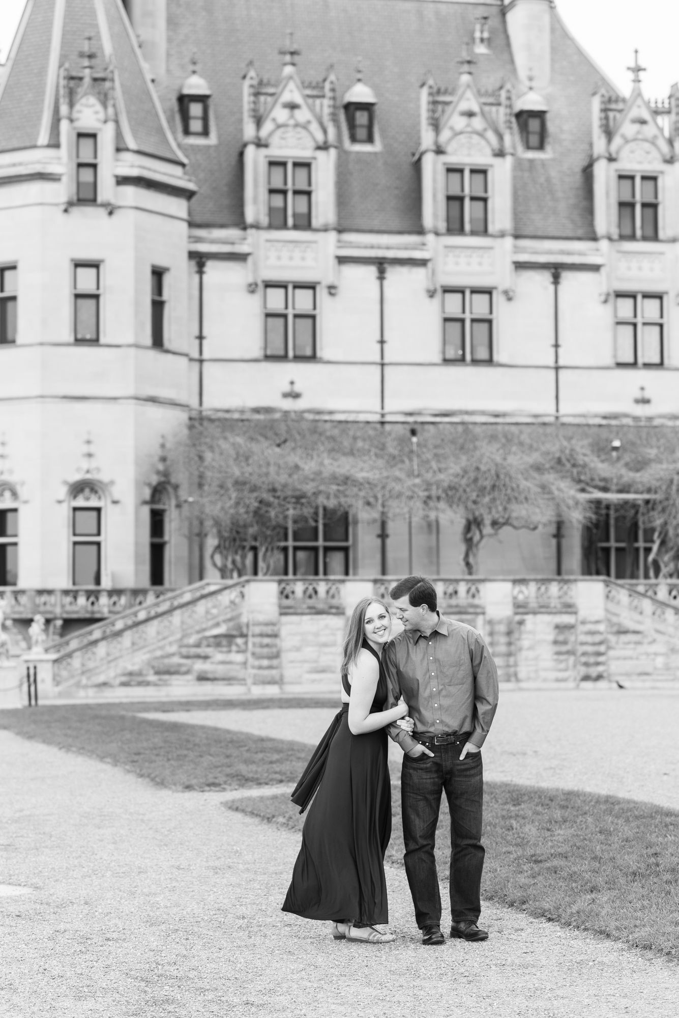 Black and white engagement photos in front of historic mansion architecture.
