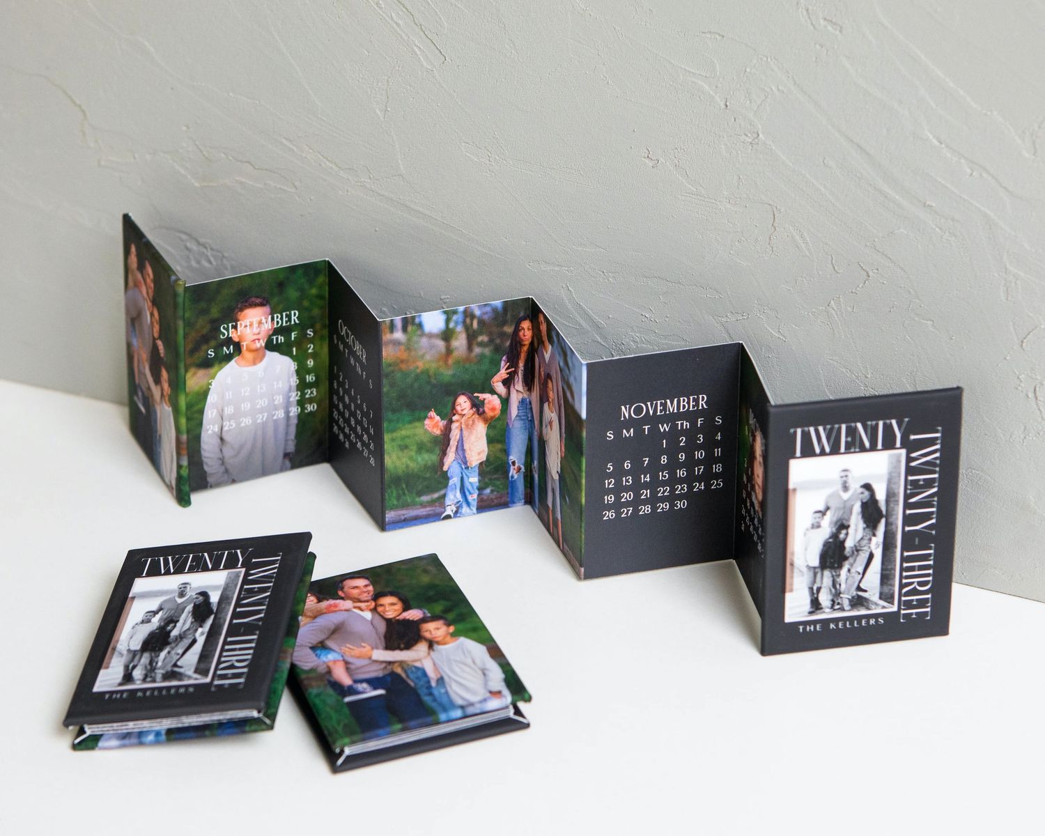 Collection of photo albums displayed on white shelf against textured wall.