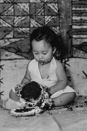 Black and white sequence of a child eating cake while laying on the ground.