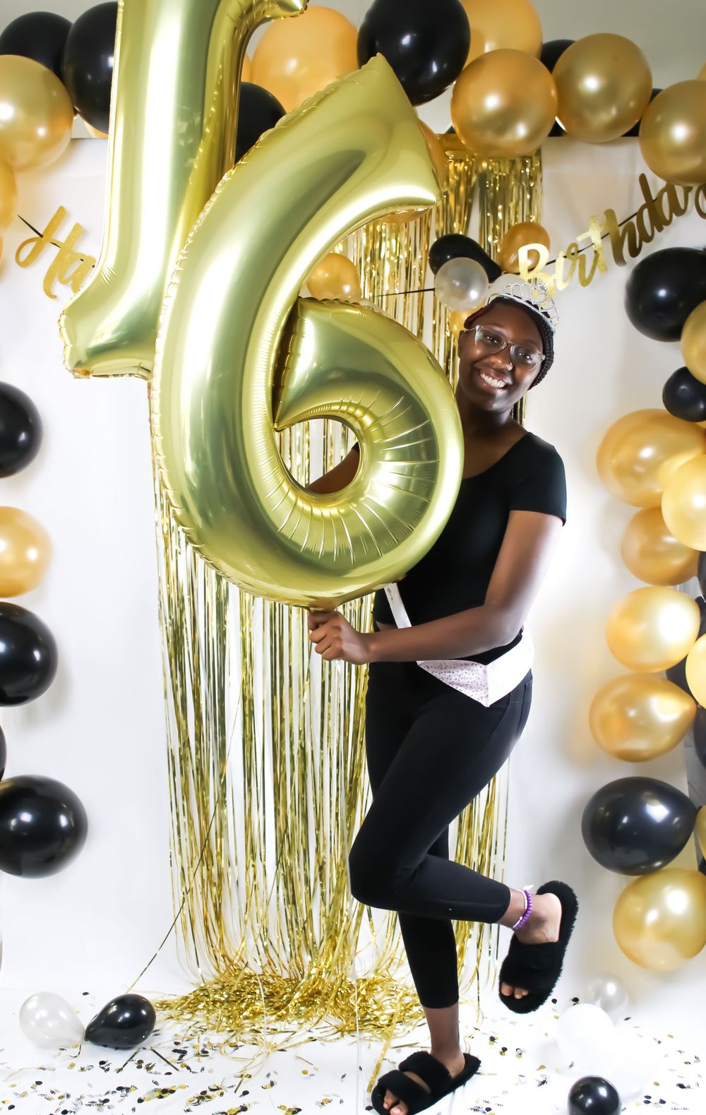 A festive celebration setup with a large gold number 6 balloon and black and gold decorations.