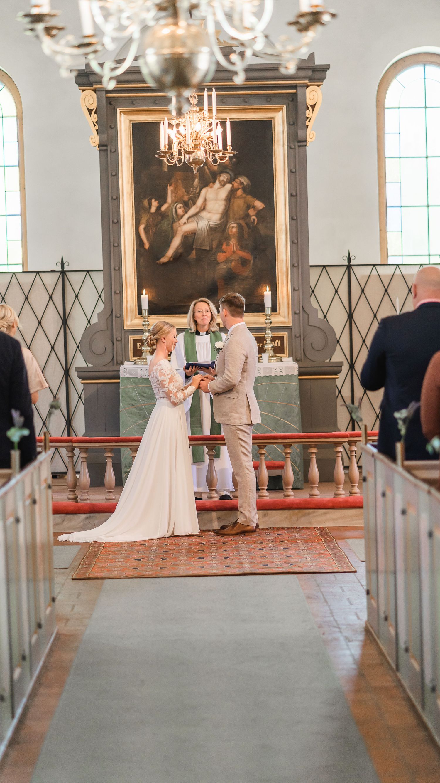 Bride and groom exchange vows before a female officiant at a church altar during wedding ceremony.